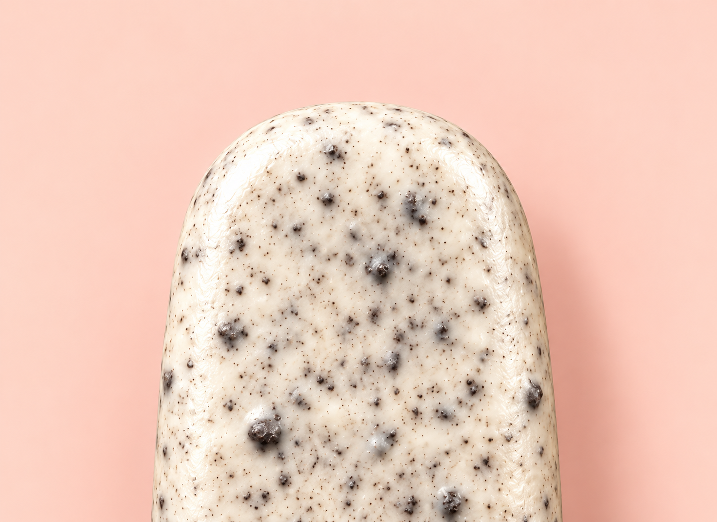 Classic cakesicle coated in a white cookies-and-cream shell on a pink background